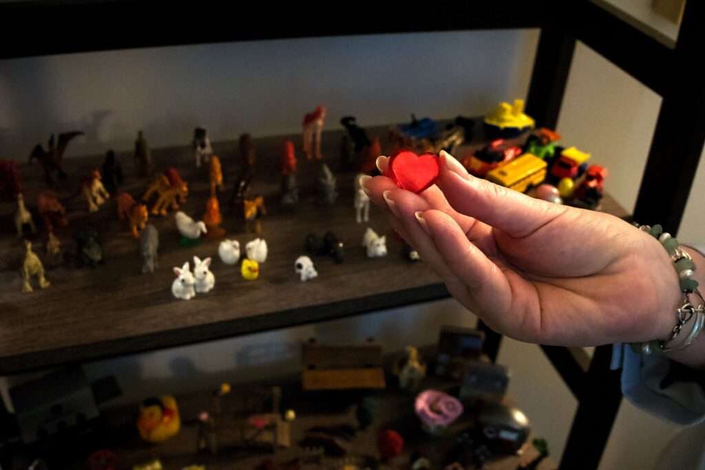 EMDR therapist holding a heart with sandtray therapy minitures in the background