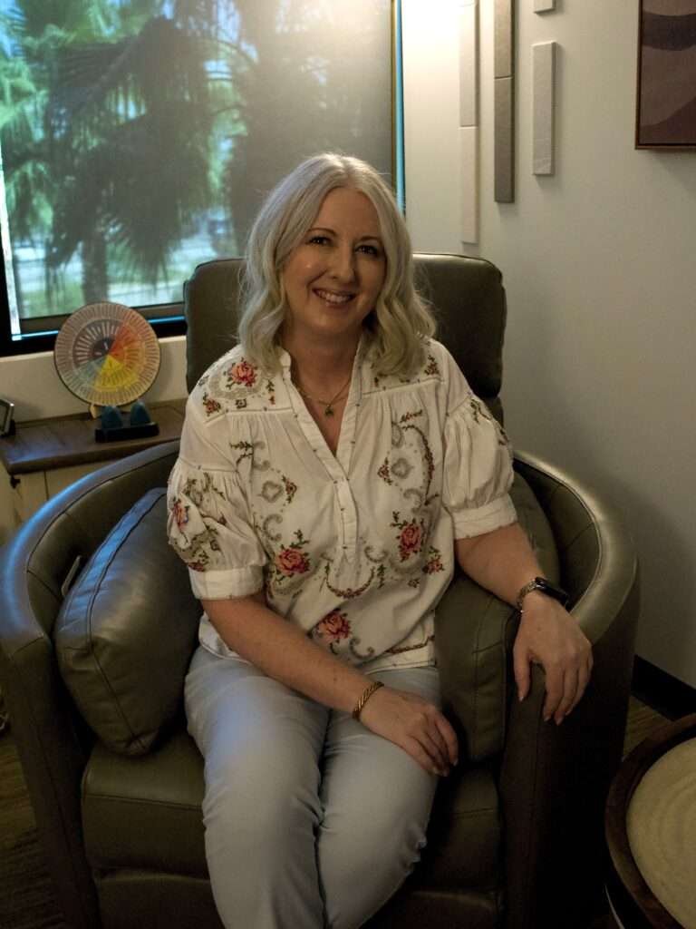 Warm inviting EMDR therapist, Allyson Dennen, in a recliner next to a bright window in Goodyear Arizona